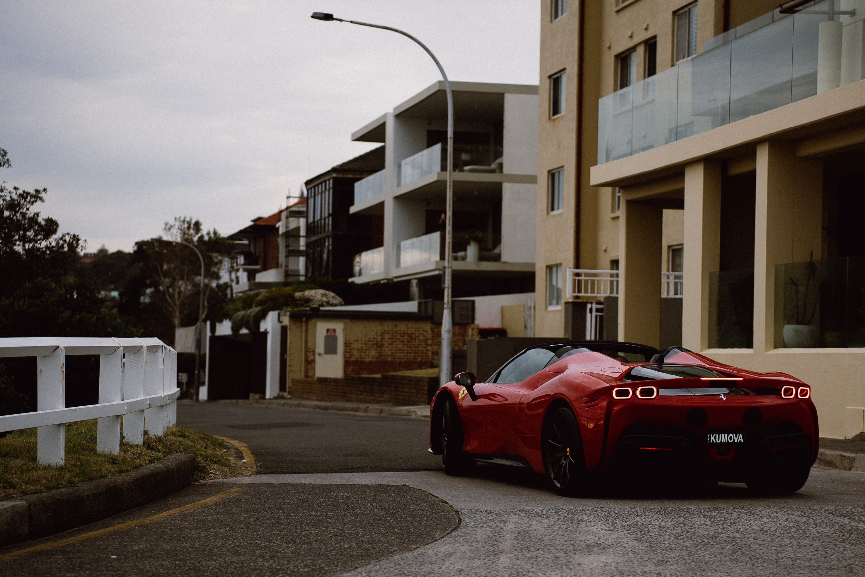 Red Ferrari parked on a residential street above the beach