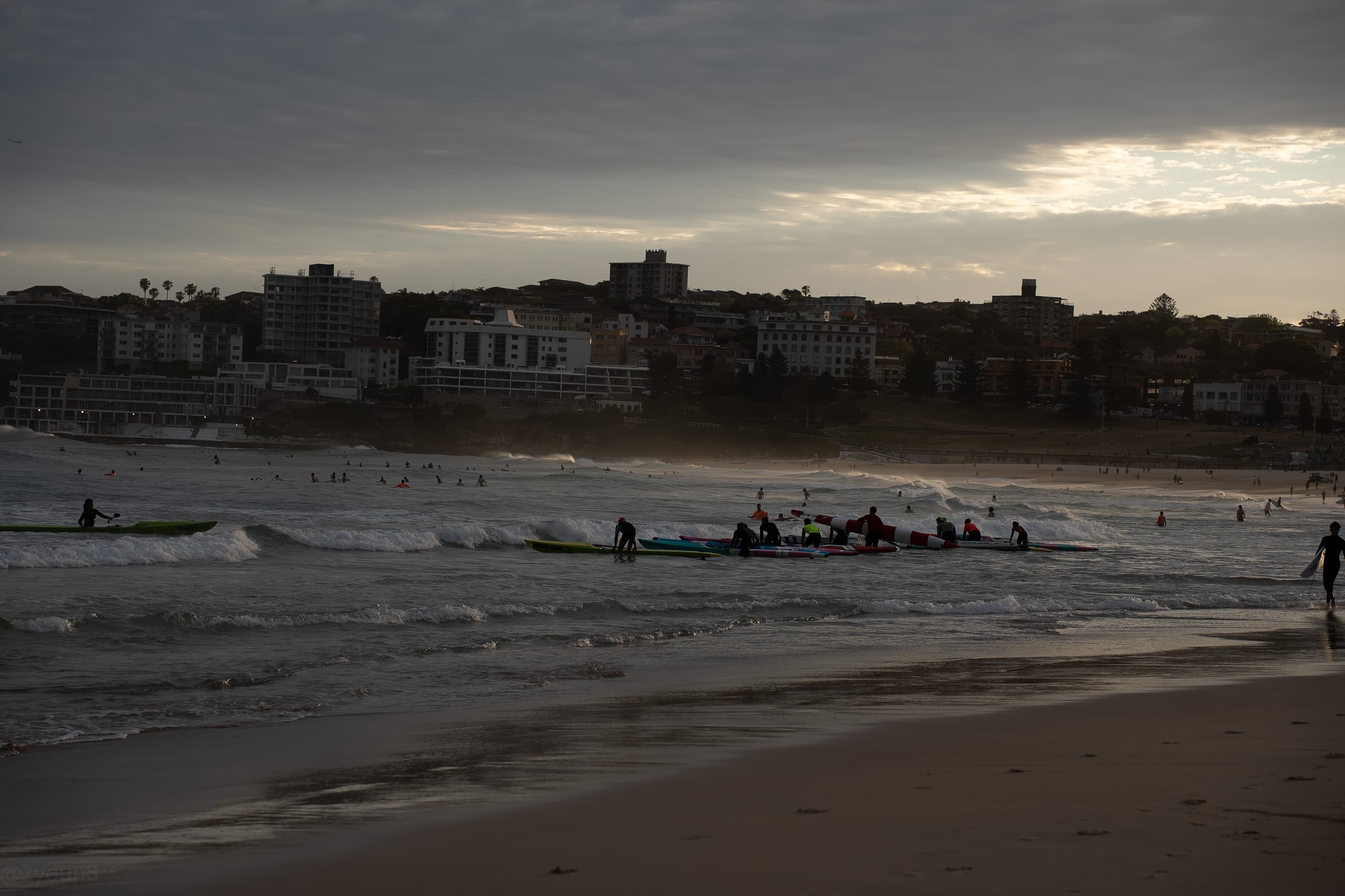 A large group of surf-ski paddlers pushing out through the break