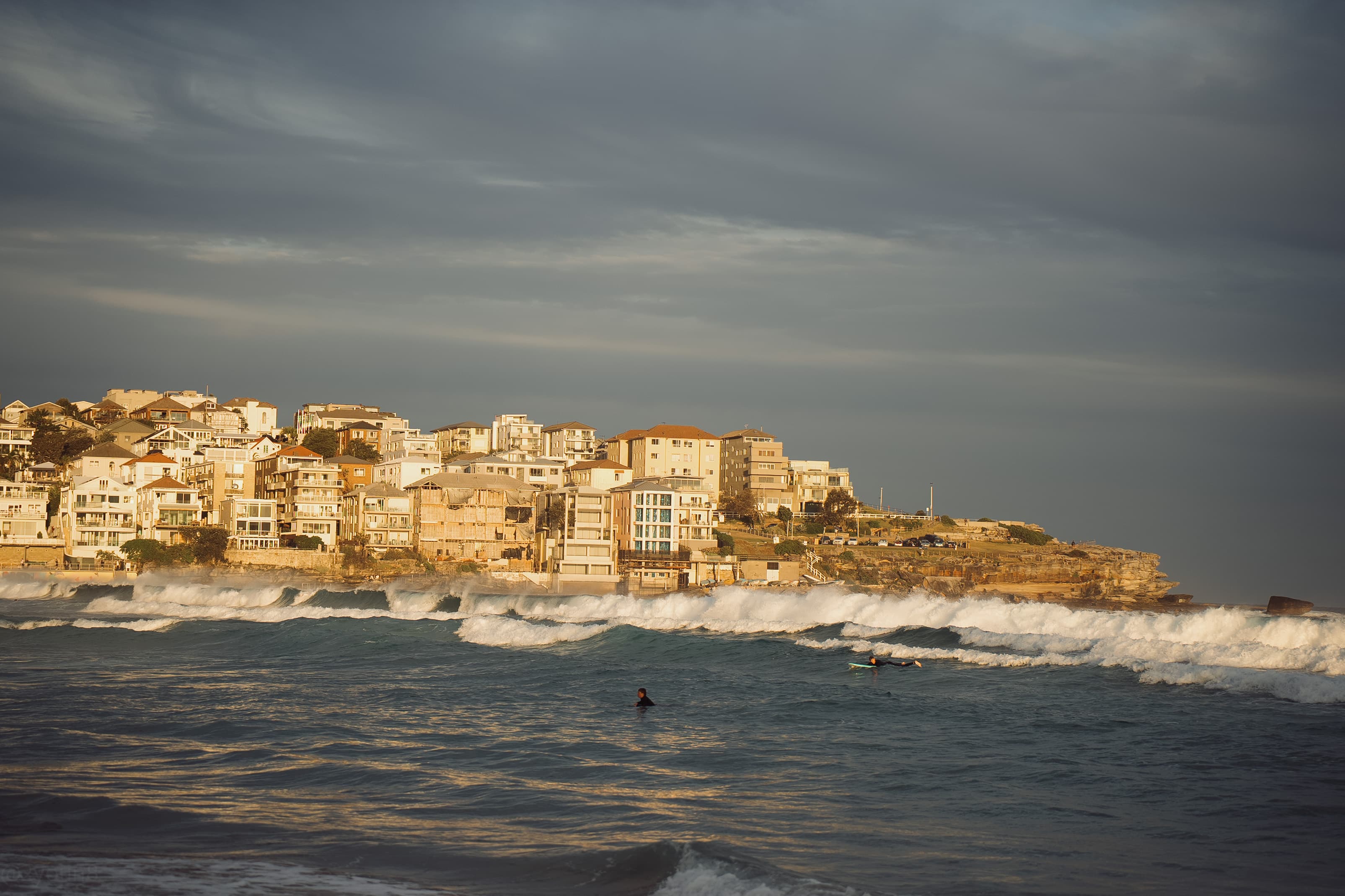 The tide rolling in below the headland in hazy evening light
