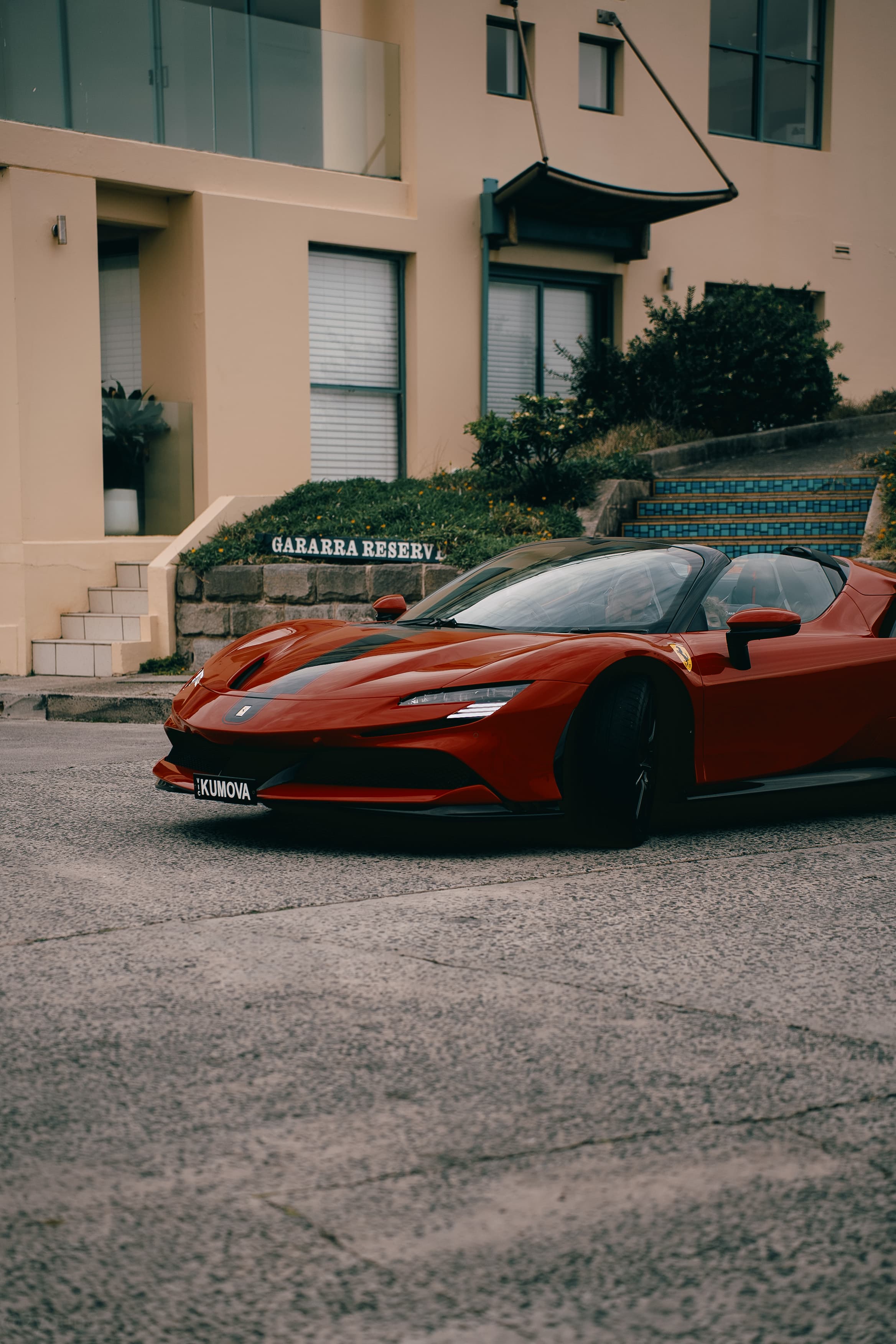 Red Ferrari parked outside a beachside apartment block