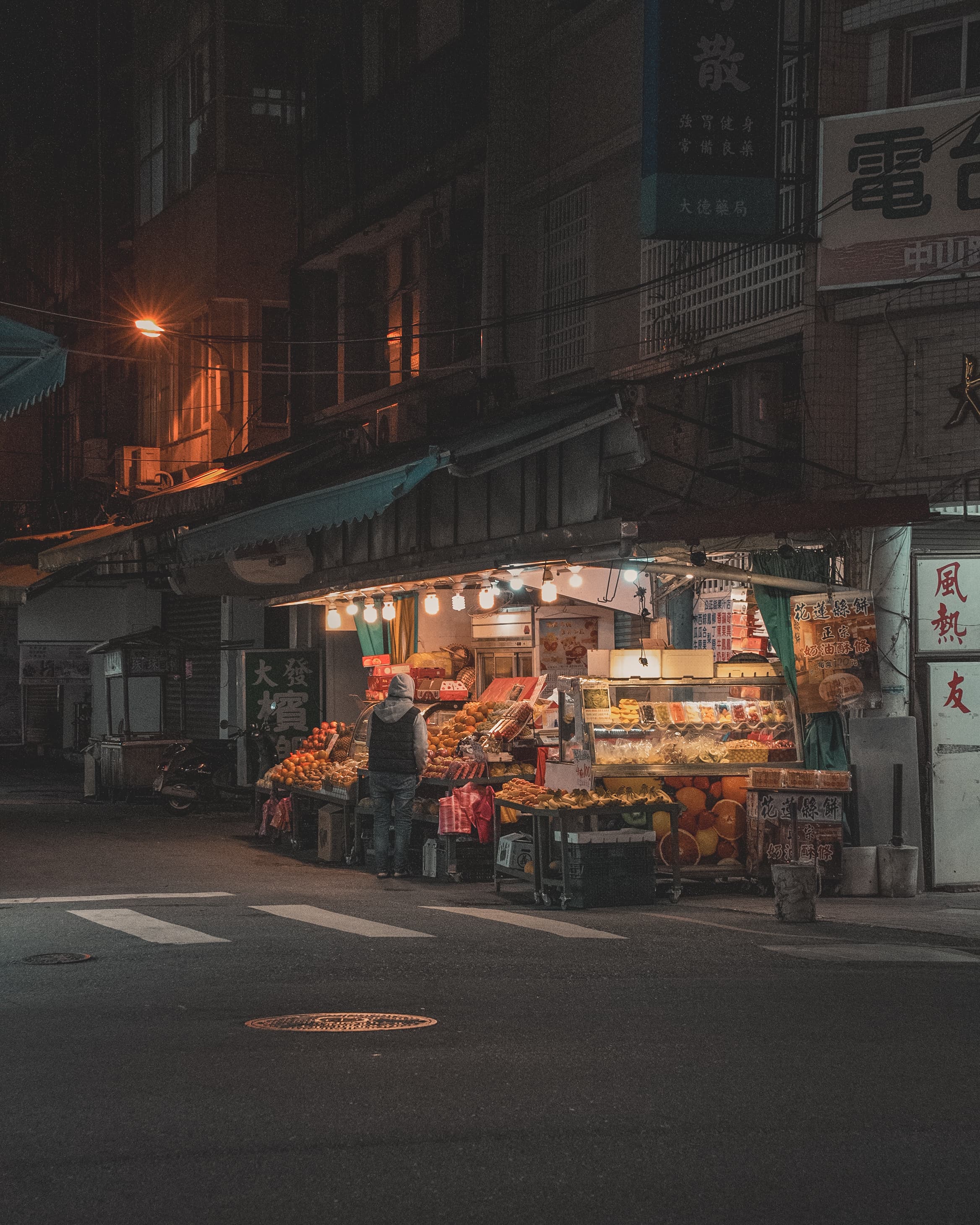 Fruit stand lit up on a night street corner