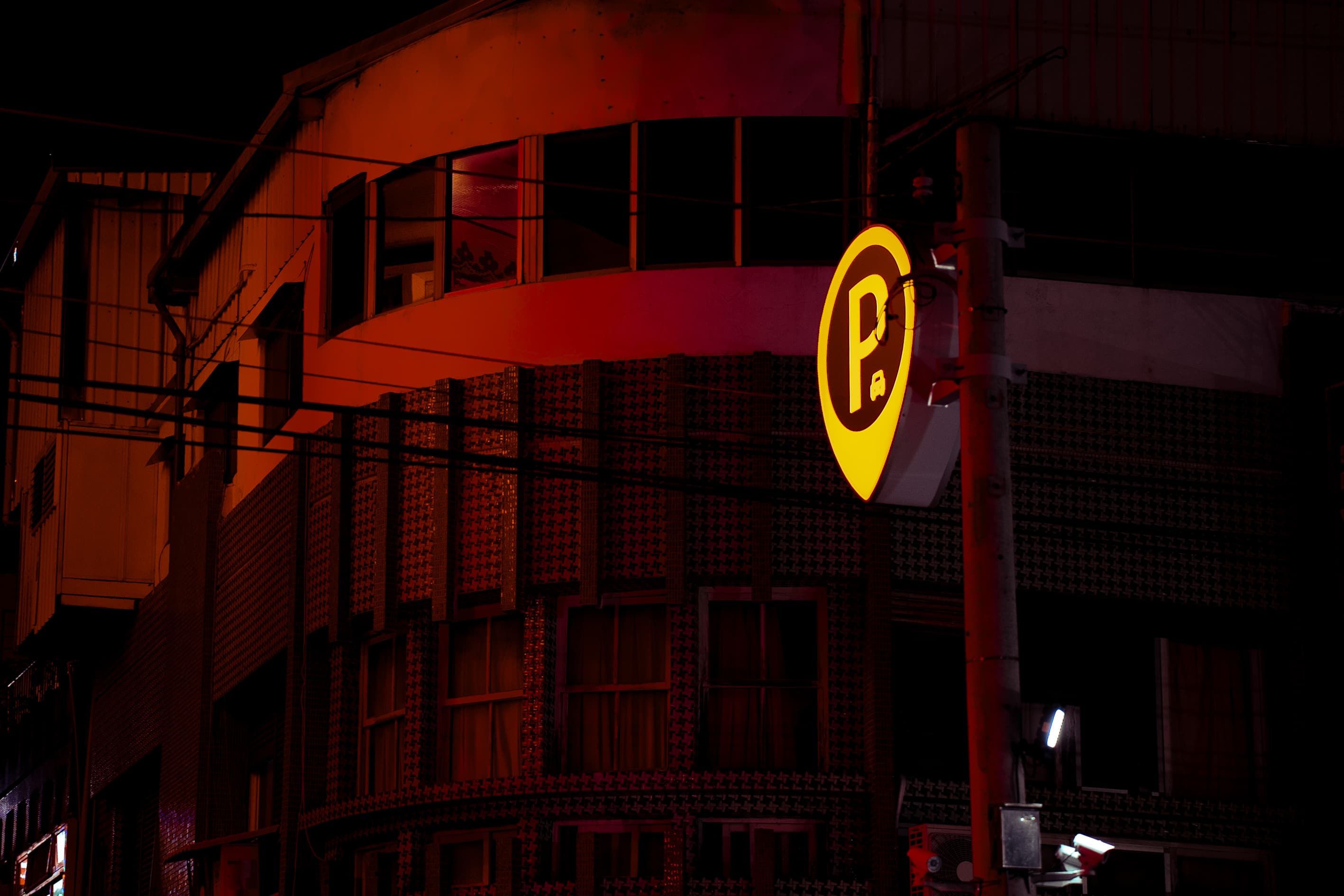 Illuminated parking sign against a building at night
